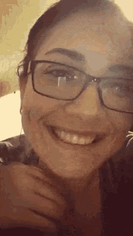 a close up of a woman wearing glasses smiling .