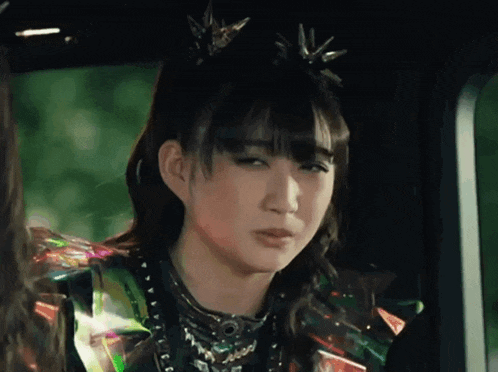 a girl with a crown on her head is making a funny face while sitting in a car .