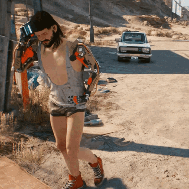 a shirtless man wearing a robotic arm is walking down the street