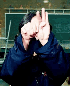 a person covering their face with their hands in front of a chalkboard