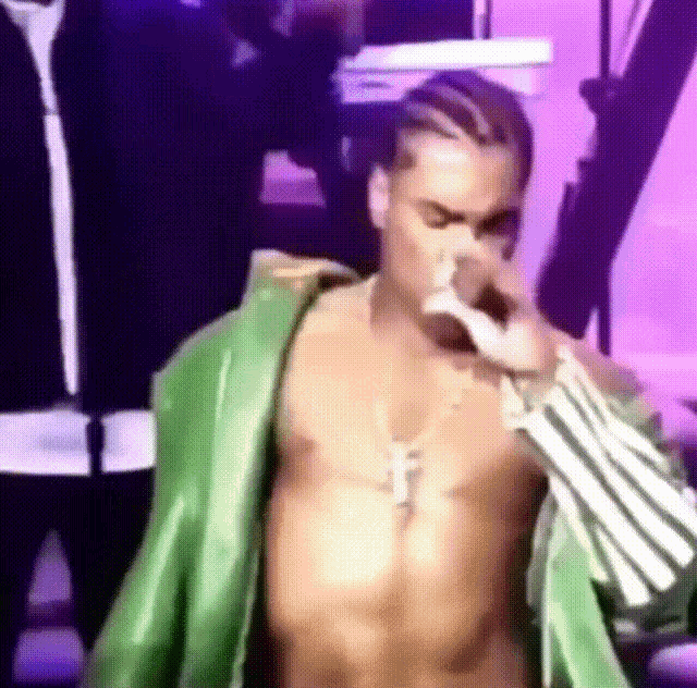 a shirtless man in a green robe is singing into a microphone