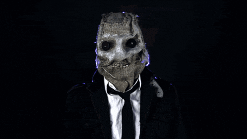a man in a suit and tie has a scarecrow mask on
