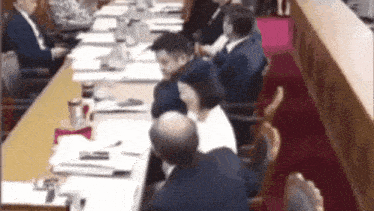 a group of people are sitting around a long table with papers on it .
