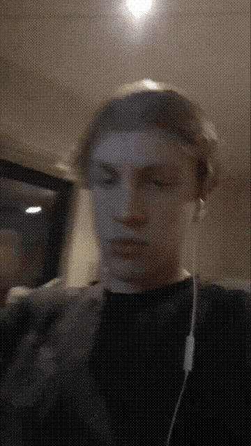 a man wearing a black shirt and headphones looks at the camera