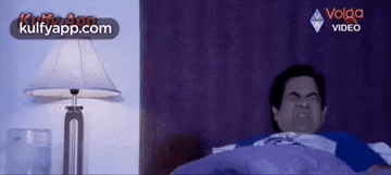 a man is laying in a bed with a lamp in the background