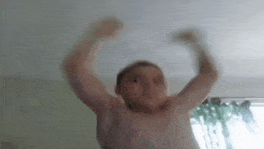 a shirtless man is flexing his muscles in a living room .