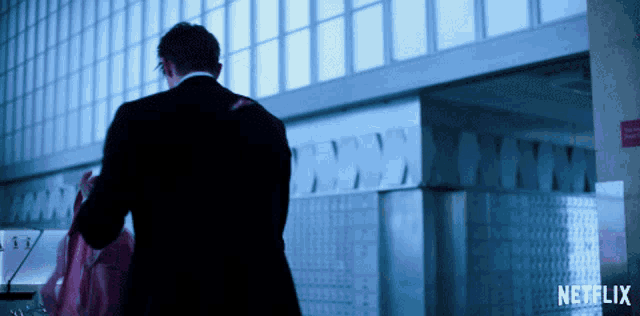 a man in a suit stands in front of a wall with netflix written on it