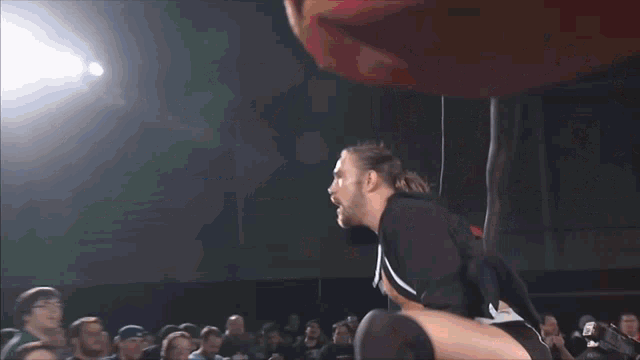 a wrestler is kneeling down in front of a ring that says " ring of honor "