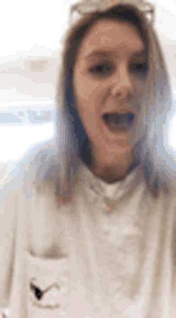 a close up of a woman wearing a white shirt and glasses .