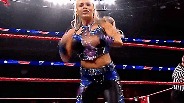 a woman in a wrestling ring with a referee in the background