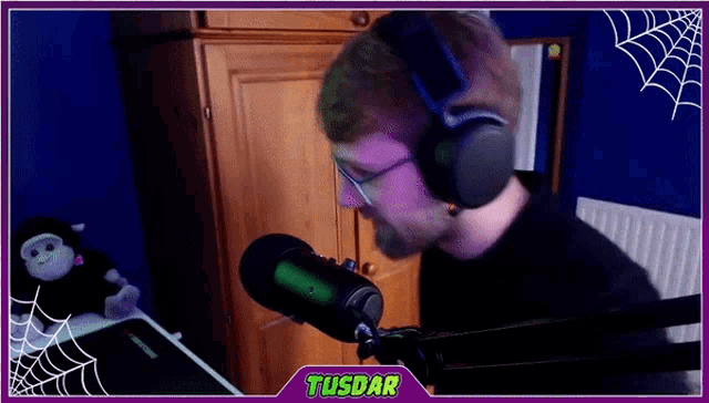 a man wearing headphones is speaking into a microphone with tusdar written on the bottom