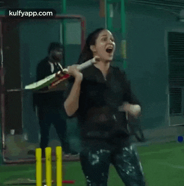 a woman is holding a cricket bat in her hand and screaming while playing cricket .