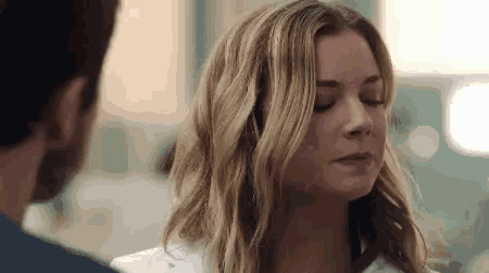 a woman in a lab coat is looking down at a man .