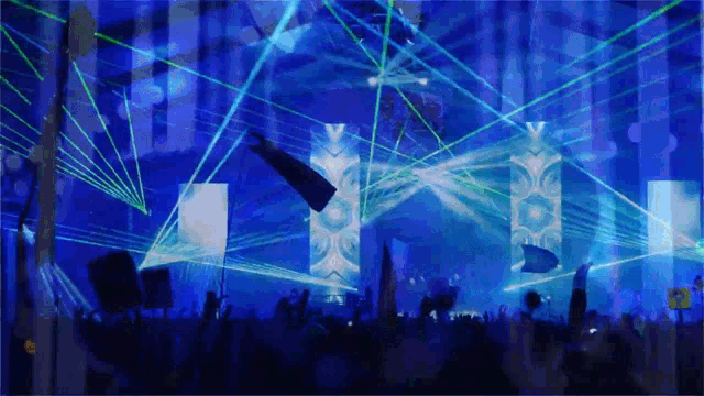 a crowd of people watching a concert with blue lights and flags flying in the air