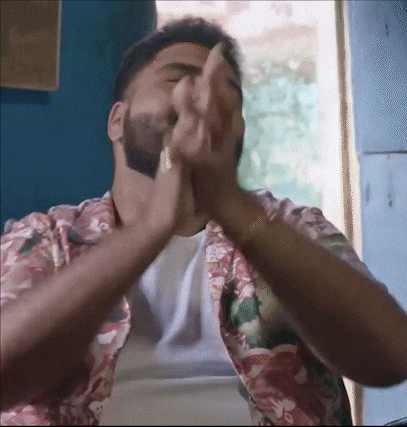 a man with a beard wearing a floral shirt is clapping his hands together .