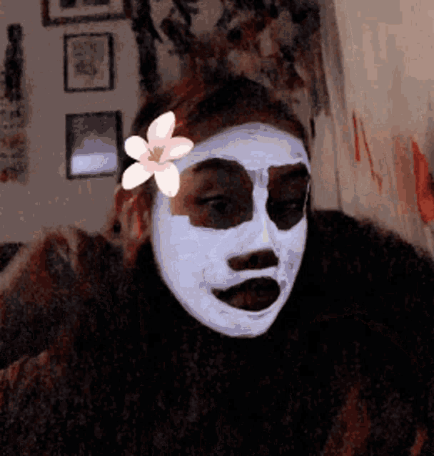 a person with a white mask on their face with a flower in their hair