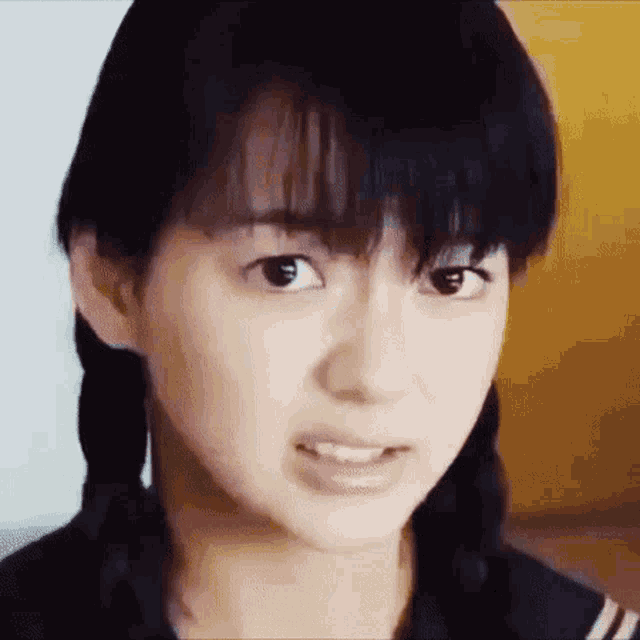 a close up of a girl 's face with pigtails and a serious look on her face .