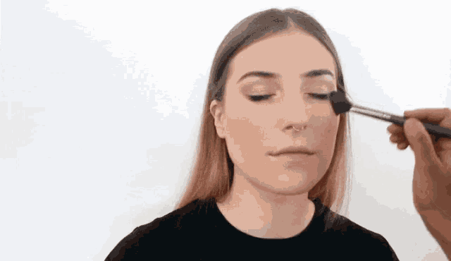 a woman is getting her makeup done by a man .