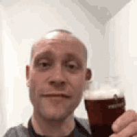 a bald man is holding a glass of beer .