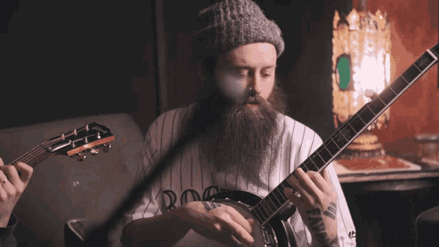 a man with a beard is playing a banjo and a guitar and his shirt says rockies
