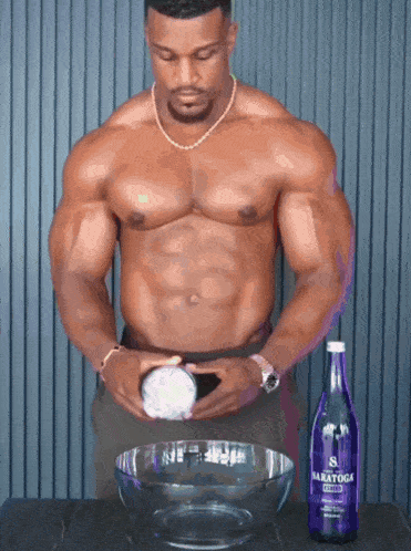a shirtless man is standing next to a bottle of baratoga