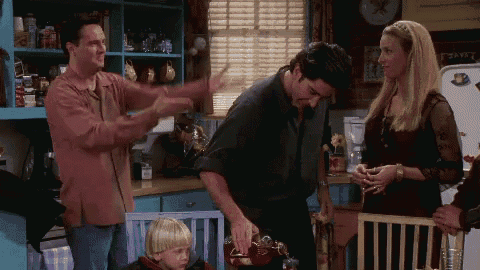 a group of people are standing in a kitchen and one of them is holding a pot .