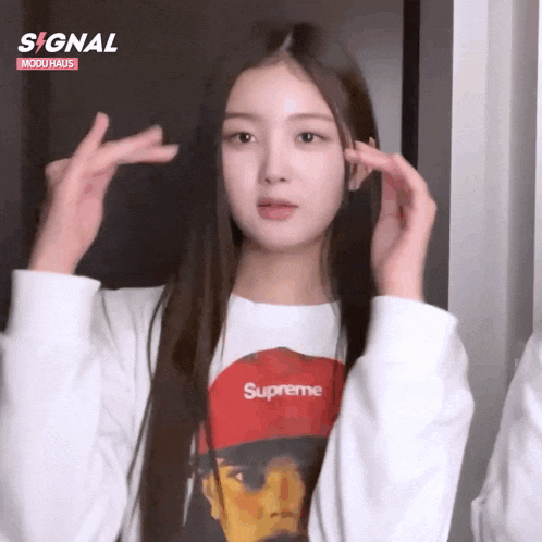a girl wearing a supreme shirt is making a gun sign