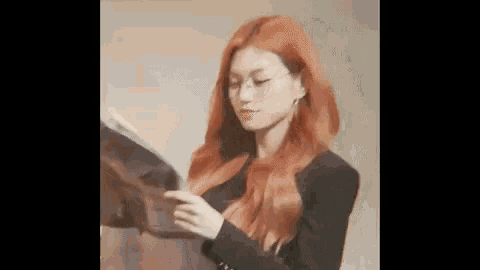 a woman with red hair is wearing glasses and a black jacket .