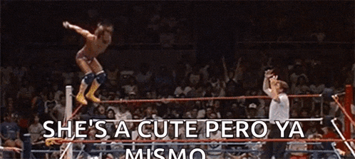 a man is jumping over a rope in a wrestling ring while a referee looks on .