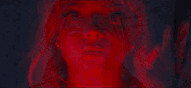 a close up of a woman 's face with a red background behind her .