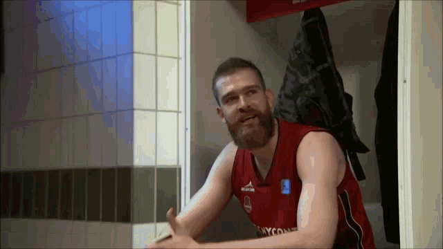 a man with a beard wears a red jersey that says skycom
