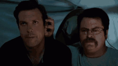 two men are sitting next to each other in a tent .