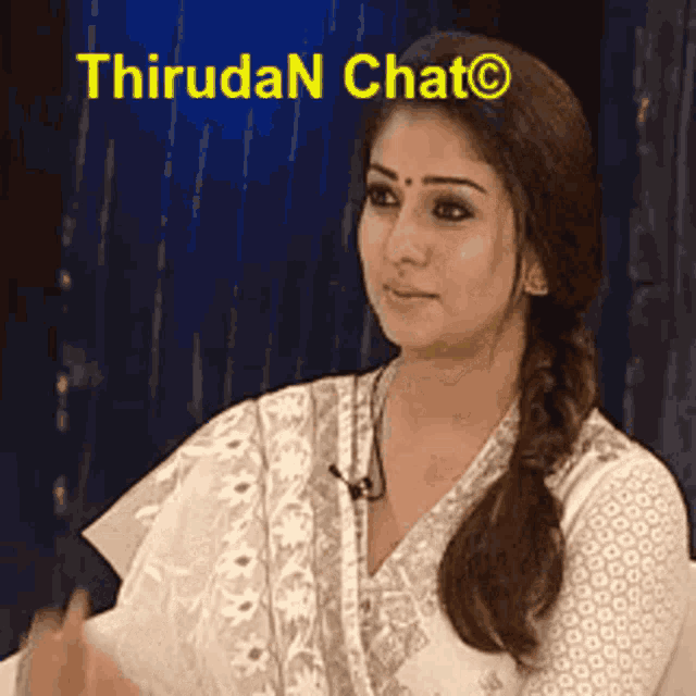 a woman in a white dress is sitting in front of a sign that says thiruda chat .