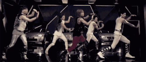 a group of people are dancing in front of a car