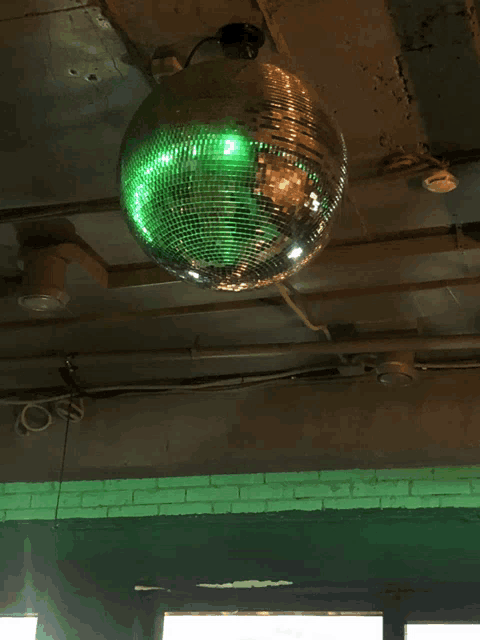a green disco ball hangs from the ceiling of a building