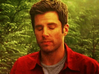 a man in a red shirt is looking down with his eyes closed .