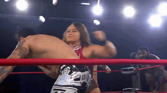 a female wrestler wearing a belt that says ' gil ' on it kicks a man in a ring