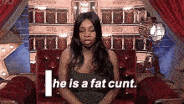 a woman is sitting on a couch with the words `` he is a fat cunt '' written on the screen .