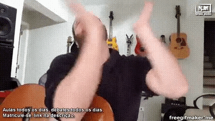 a man is playing a guitar in a room with guitars on the wall