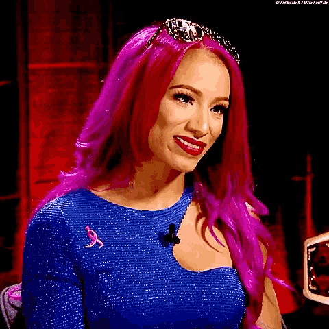 a woman with pink hair is wearing a blue dress and smiling .