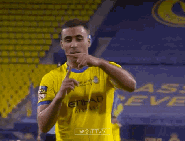 a soccer player wearing a yellow etihad airlines shirt