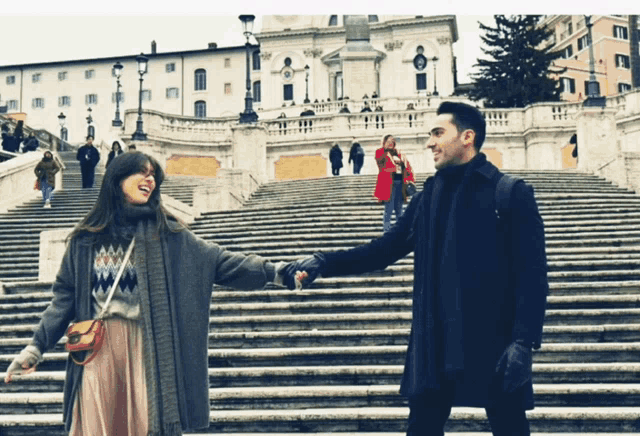 a man and a woman are holding hands on a set of steps