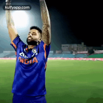 a man in a blue shirt is raising his arms in the air .