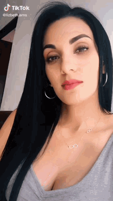 a woman with long black hair is wearing a necklace with infinity symbols on it .