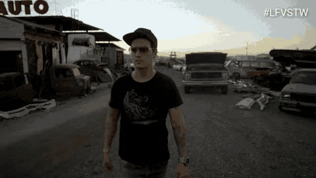 a man wearing sunglasses and a hat walks in front of a building that says auto