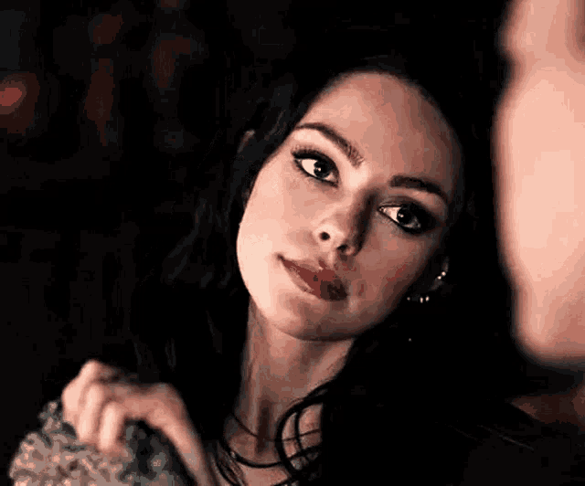 a woman is looking at a man in a dark room and making a funny face .