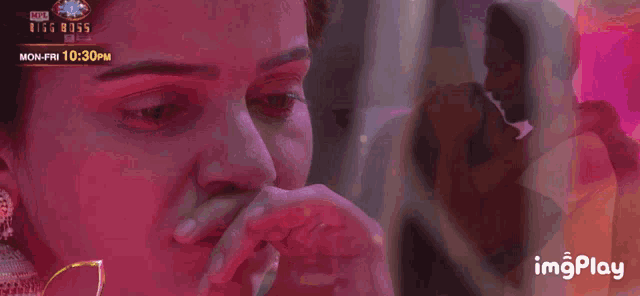 a woman is crying in front of a bigg boss ad