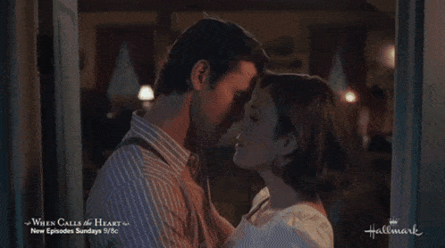 a couple kissing in front of a sign that says hallmark
