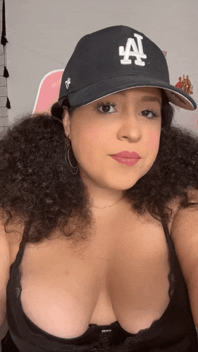 a woman is wearing a la hat and a black bra