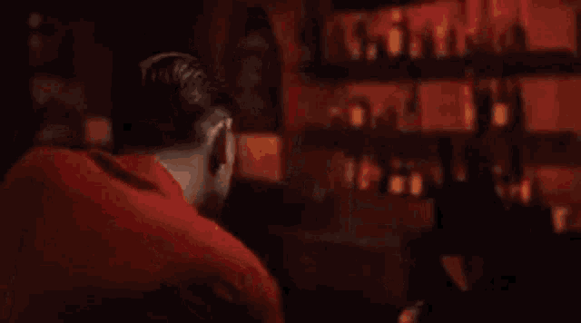 a man is sitting at a bar drinking a beer from a glass .